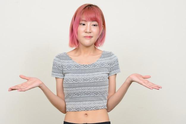 Confused young woman with pink hair and gray top shrugging