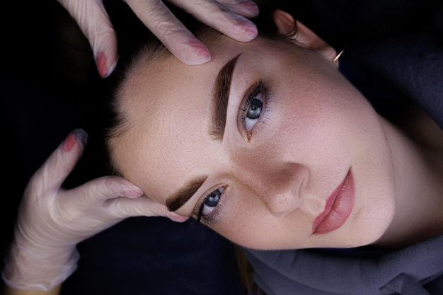 A close-up image of a woman receiving a facial treatment with a skincare professional's hands in gloves touching her face.