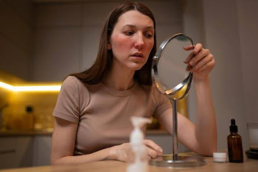 Woman examining her face in a handheld mirror at home